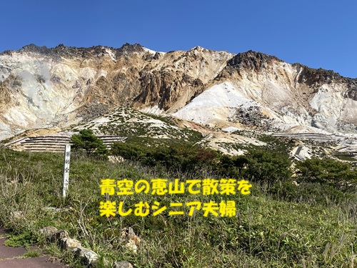 青空の恵山で散策を楽しむシニア夫婦