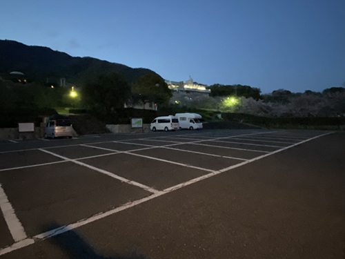 夜間公園の駐車場に泊まるキャブコンとバンコン